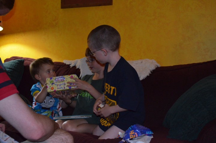 Abby and Aiden helping Macklan open his birthday presents.