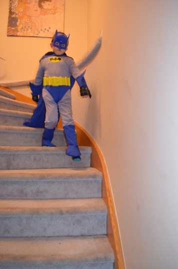 Aiden strutting down the stairs as Batman